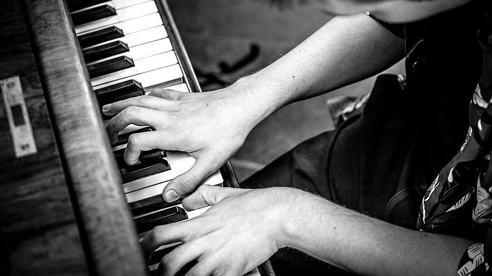 Svart-vit bild med en person som spelar piano.