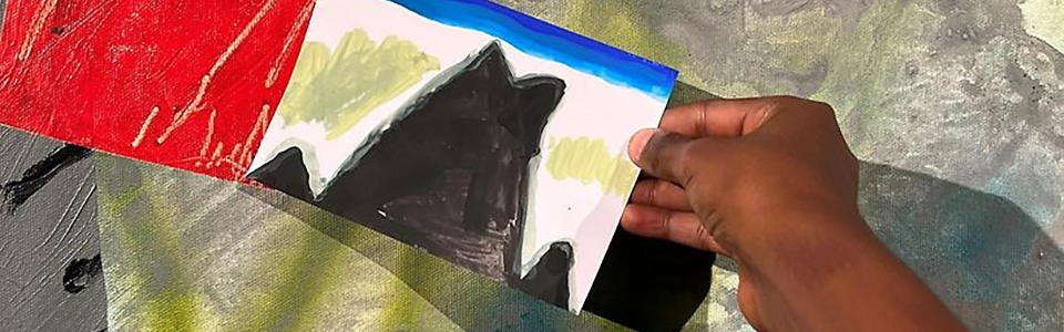 En hand som håller i en teckning. Teckningen visar en svart silhuett.