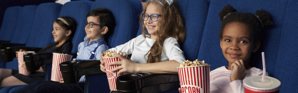 Fyra barn tittar på film och äter popcorn.