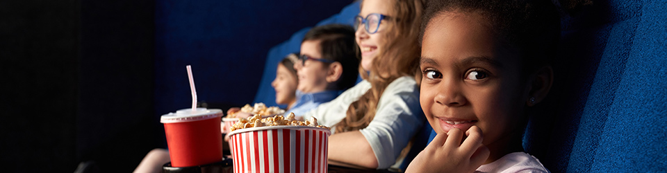 Barn som tittar på film med popcorn i knät.