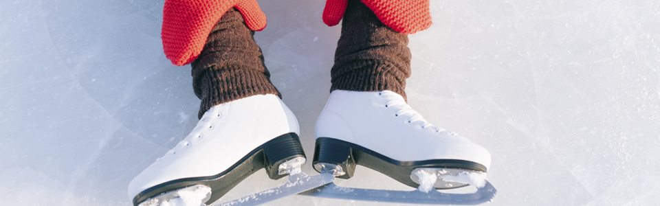 Ett par vita skridskor på en person som sitter på isen.