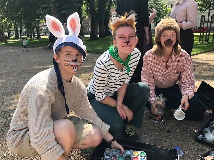 Tre tjejer som är målade i ansiktet som kaniner och är utklädda med kaninöron