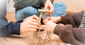 Barn bygger ett litet torn av pinnar och papp.